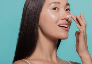 Primo piano di donna asiatica che si spalma la crema sul naso