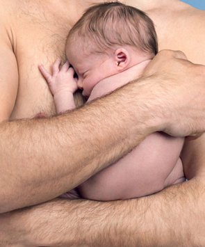 Particolare di uomo a torso nudo che abbraccia neonato